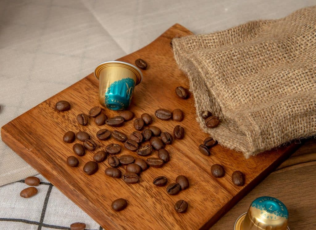 Fèves de café et capsules posées sur une planche en bois