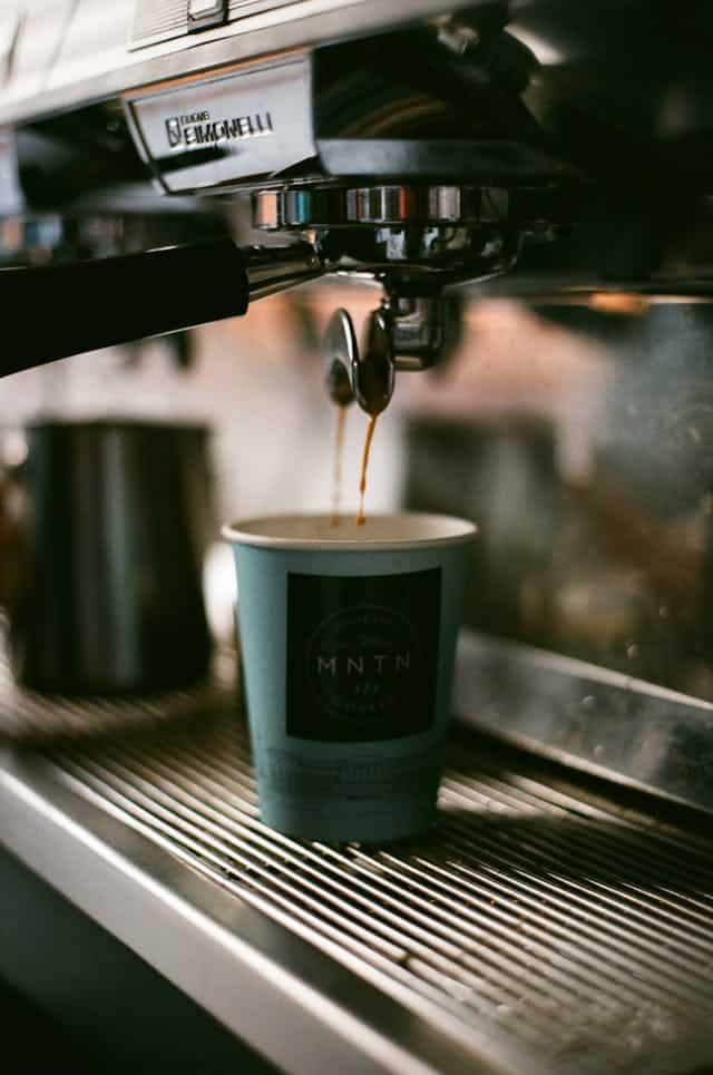 Café qui coule doucement depuis un cafetière à grains
