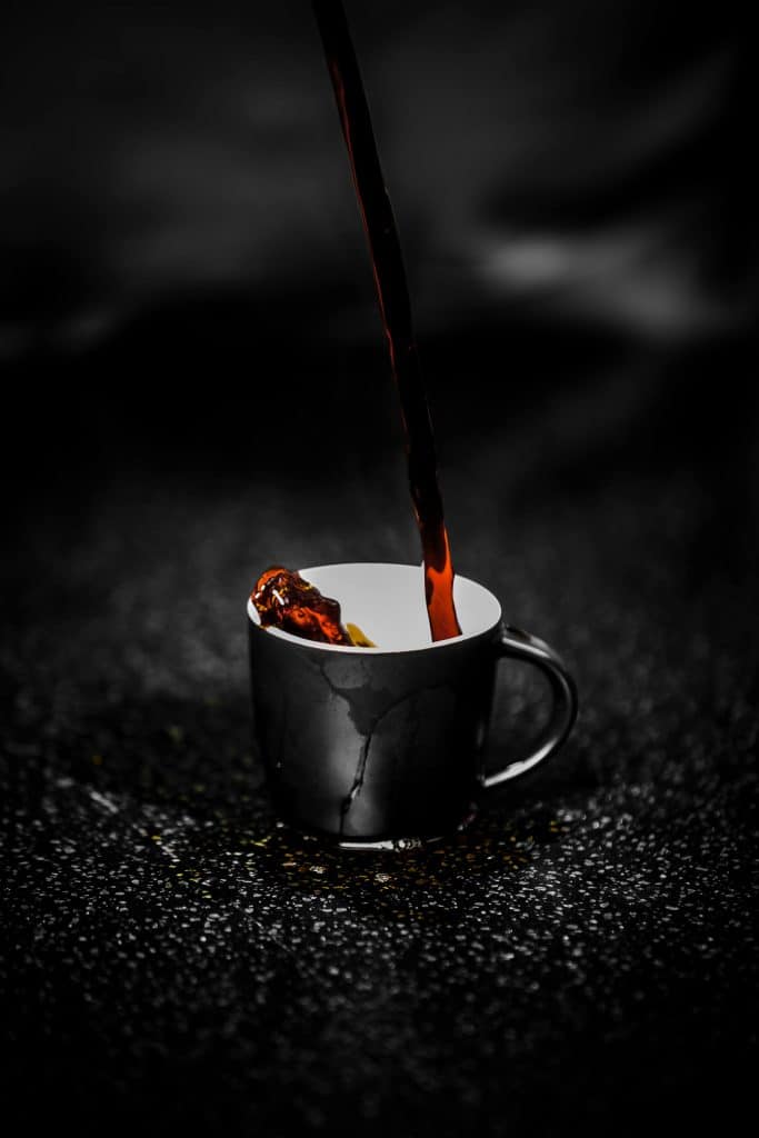 Café intense qui coule dans une tasse, avec un décor noir